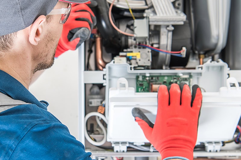 Schedule Your Annual Furnace Inspection Now. A technician inspecting a furnace.